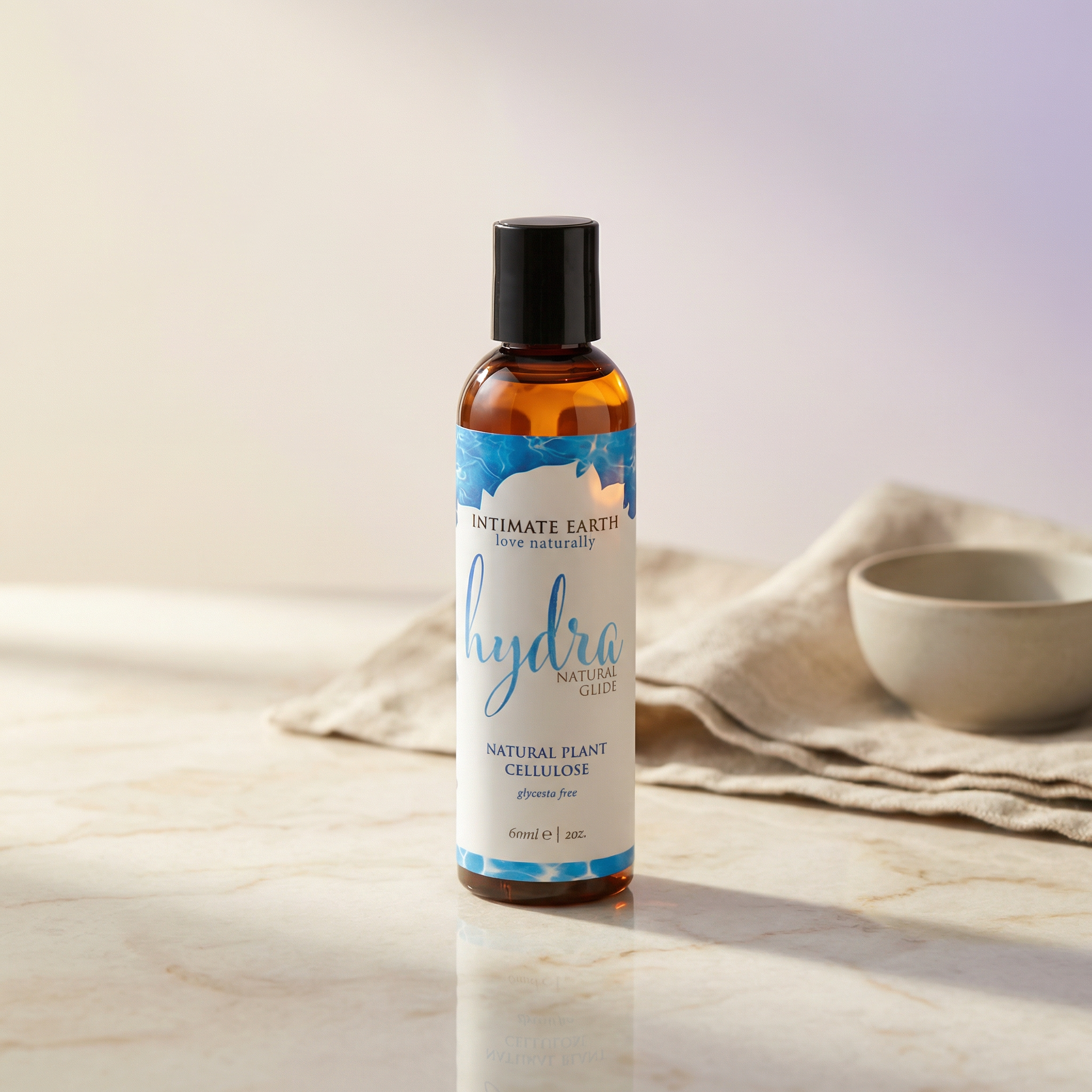 Intimate Earth Hydra glijmiddel amberkleurige fles 60 ml op marmeren ondergrond met doek