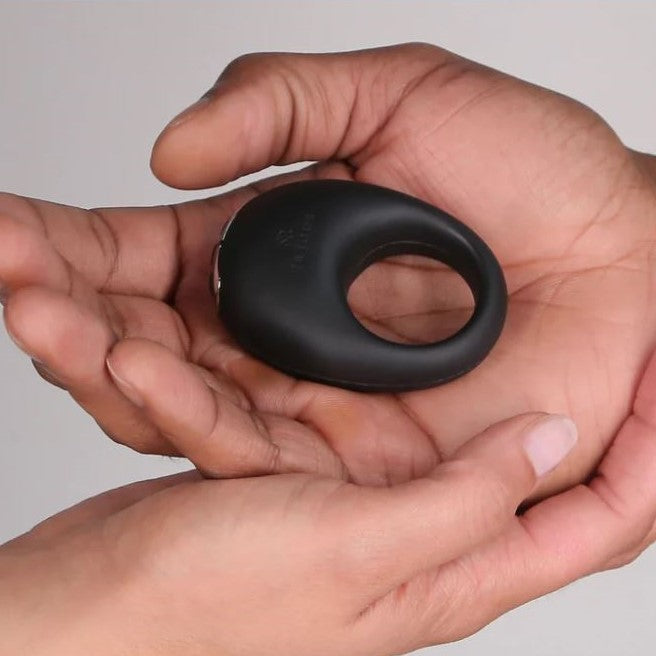 Je Joue Mio zwarte siliconen vibrerende cockring vastgehouden in twee handen, compact formaat