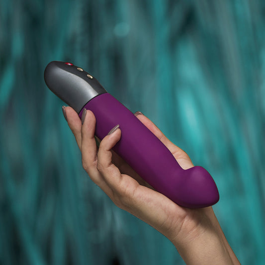 Paarse Fun Factory Stronic G Forte g-spot pulsator vastgehouden in een hand, zijaanzicht